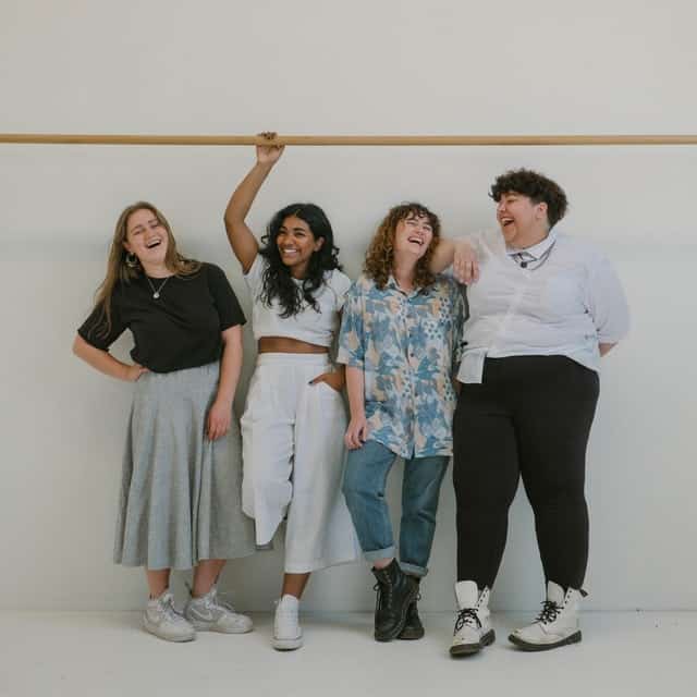 A group of four smiling friends of different races and gender identities.